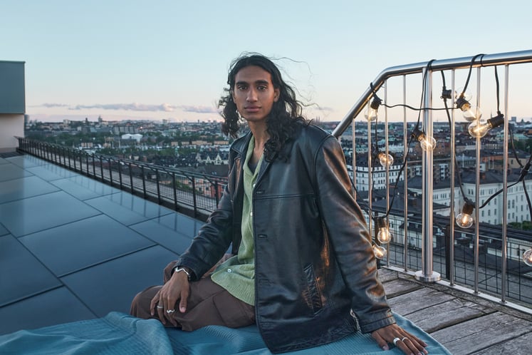 Young man in front of solar cells looking into camera