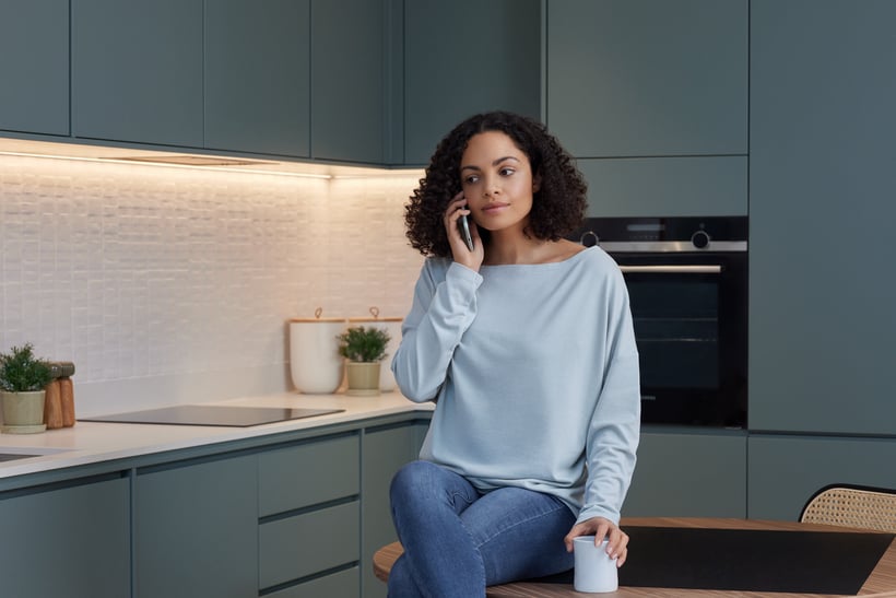 Woman speaking on phone in kitchen.